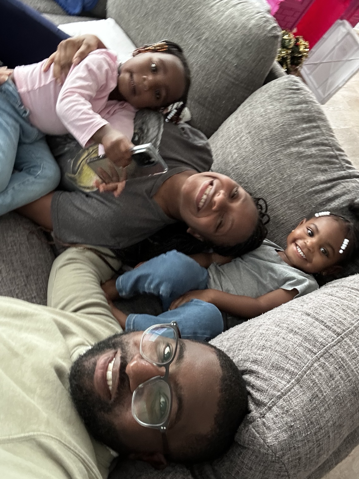 Calvin, Kneisha, and their daughters relaxing together on the couch